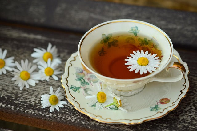 Tea in a cup with a floating Daisy. 